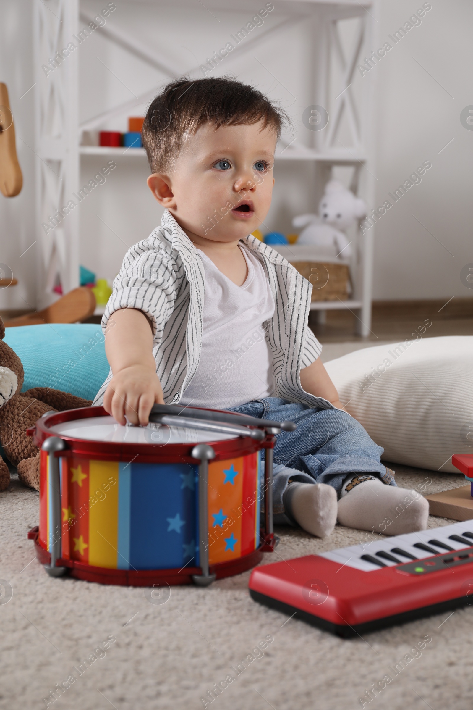 Photo of Cute little boy with drumsticks and toy drum at home