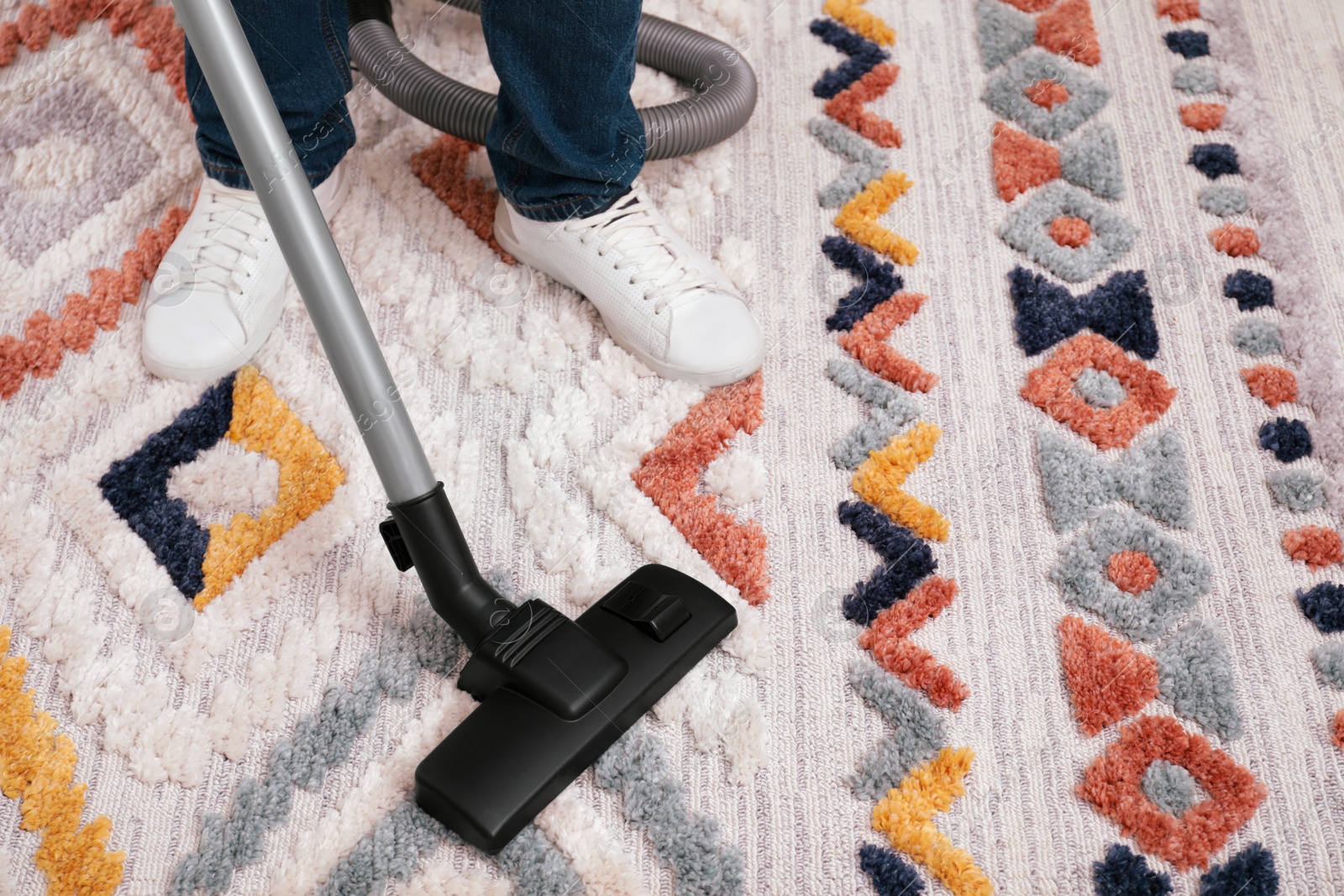 Photo of Man cleaning carpet with vacuum cleaner at home, closeup