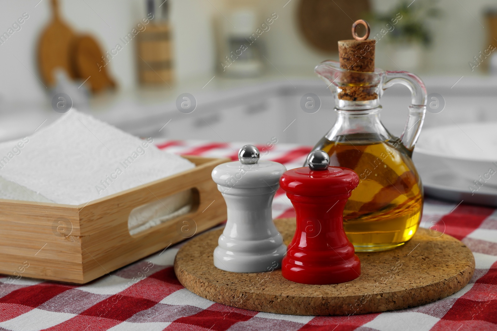 Photo of Ceramic salt and pepper mills with bottle of oil on kitchen table