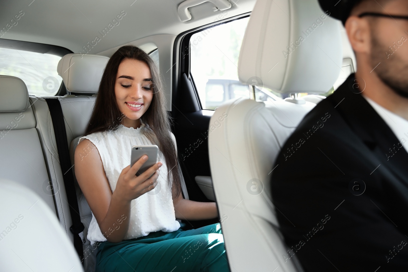 Photo of Young businesswoman with driver in luxury car. Chauffeur service