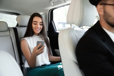Photo of Young businesswoman with driver in luxury car. Chauffeur service