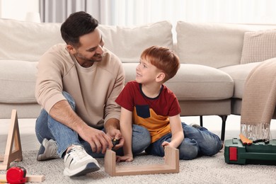 Father and son repairing shelf together at home