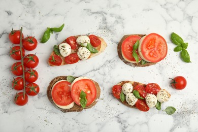 Photo of Delicious sandwiches with mozzarella, fresh tomatoes and basil on white marble table, flat lay