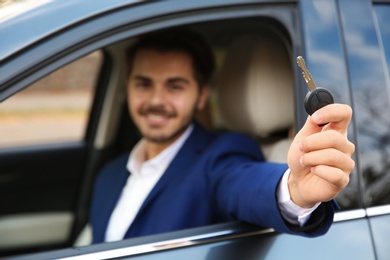 Young man holding car key in auto. Driving license test