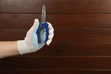 Photo of Man with needle nose pliers on wooden background, closeup. Space for text