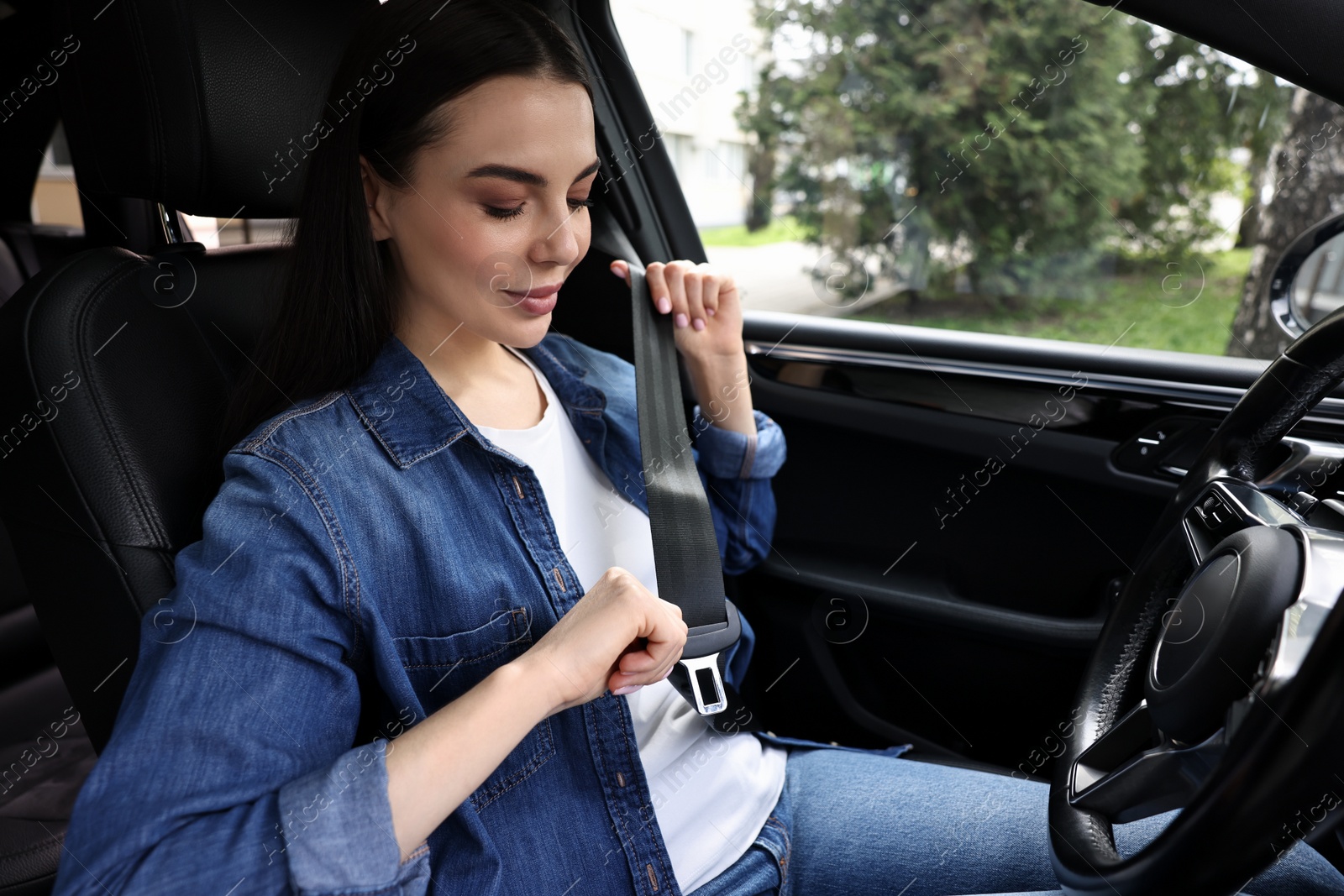 Photo of Woman fastening safety seat belt inside modern car