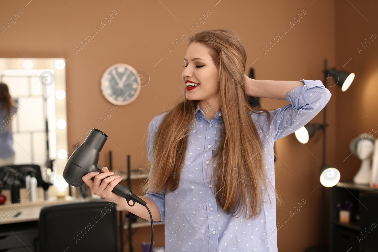 Photo of Professional hairdresser with blow dryer in beauty salon