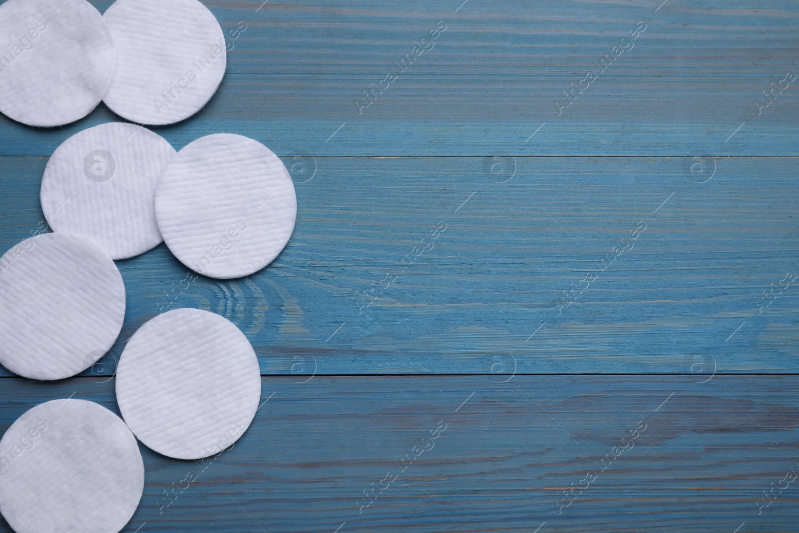 Photo of Many clean cotton pads on light blue wooden table, flat lay. Space for text