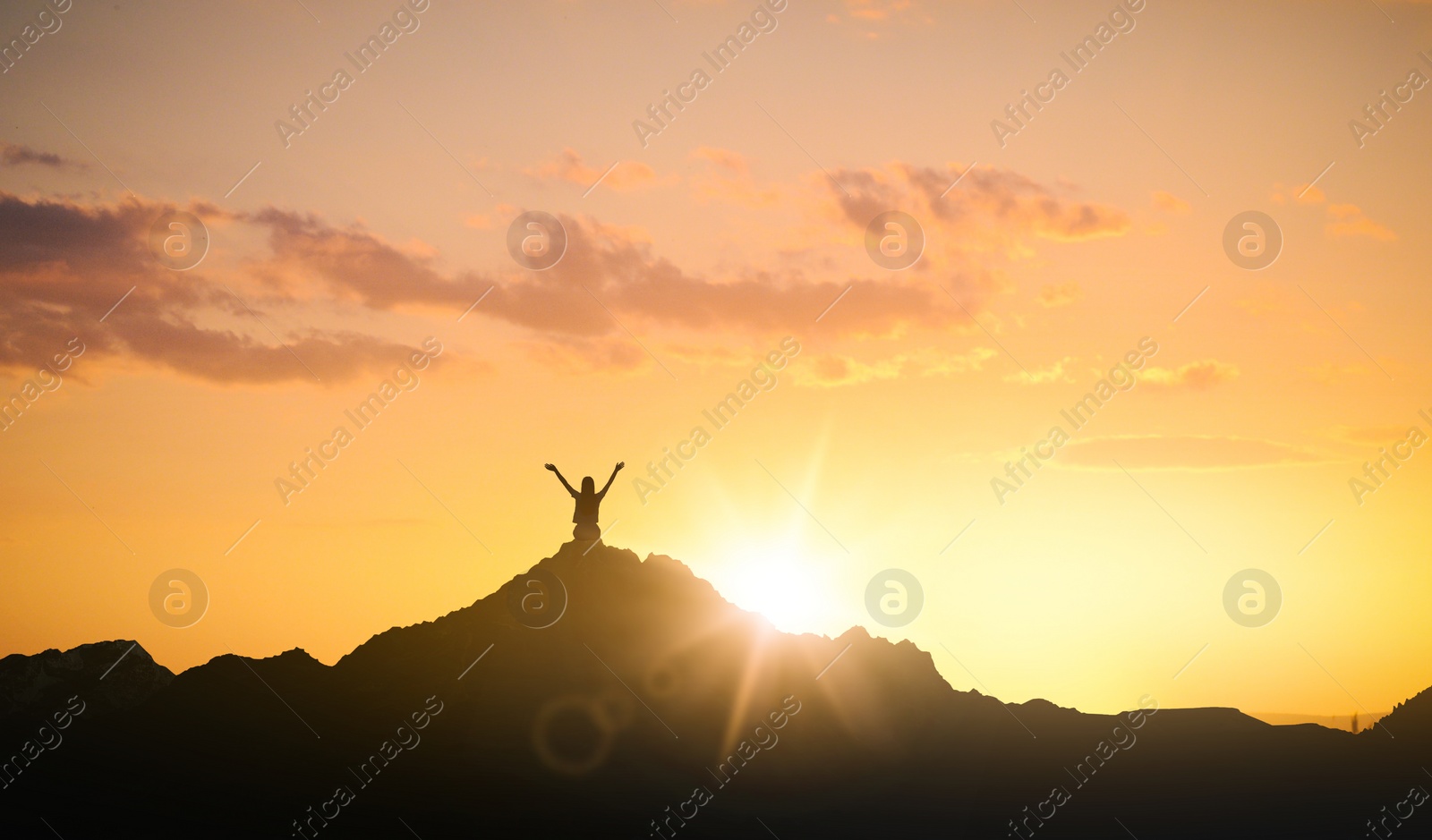 Image of Silhouette of woman in mountains under sky at sunset