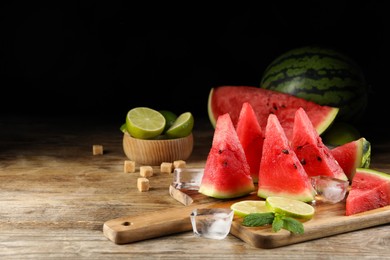 Photo of Tasty juicy watermelon, ice and lime slices on wooden table, space for text