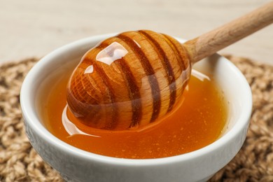 Dipper with honey in bowl on table, closeup