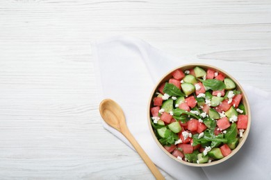 Photo of Delicious salad with watermelon, cucumber, arugula and feta cheese on white wooden table, flat lay. Space for text