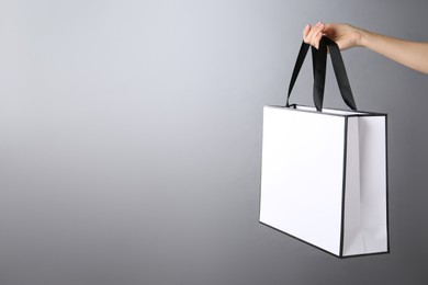 Photo of Woman holding paper bag on grey background, closeup with space for text. Mockup for design