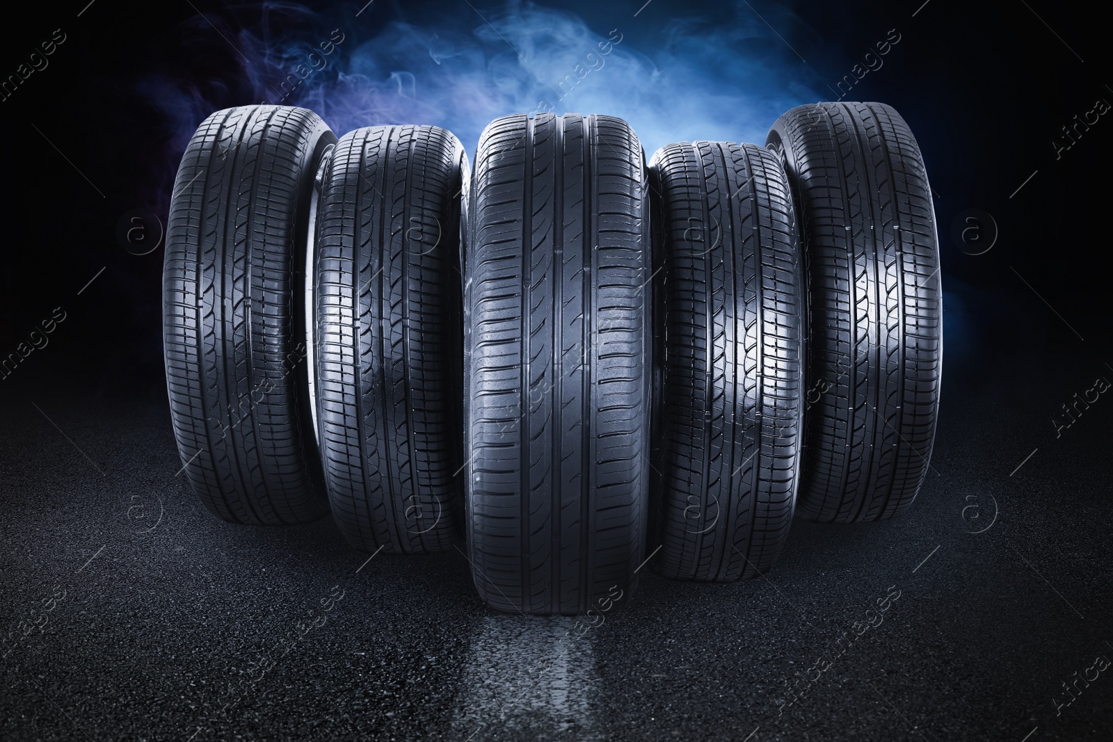 Image of Car tires and smoke on road against black background