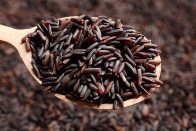 Photo of Black rice in wooden spoon, closeup view