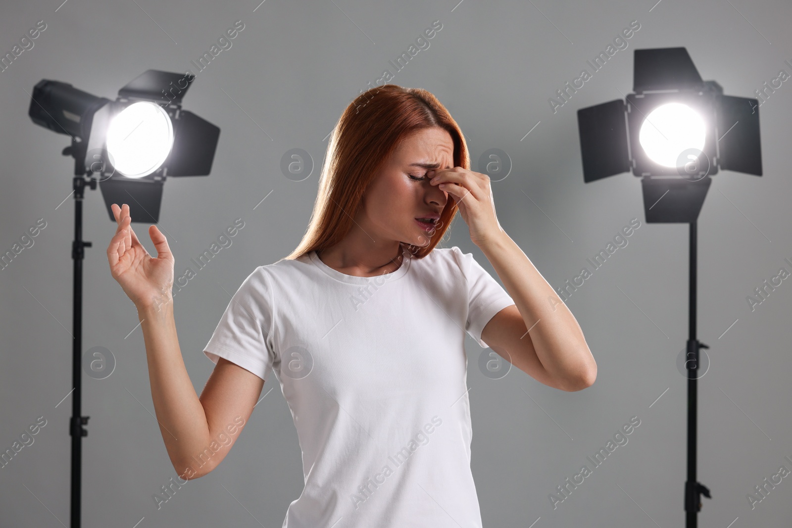 Photo of Casting call. Emotional woman performing on grey background in studio