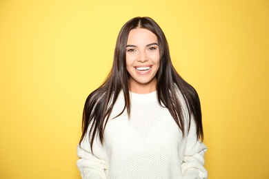 Image of Happy young woman wearing warm sweater on yellow background 