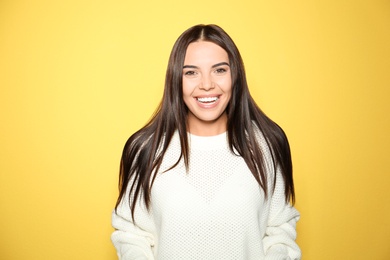 Happy young woman wearing warm sweater on yellow background 