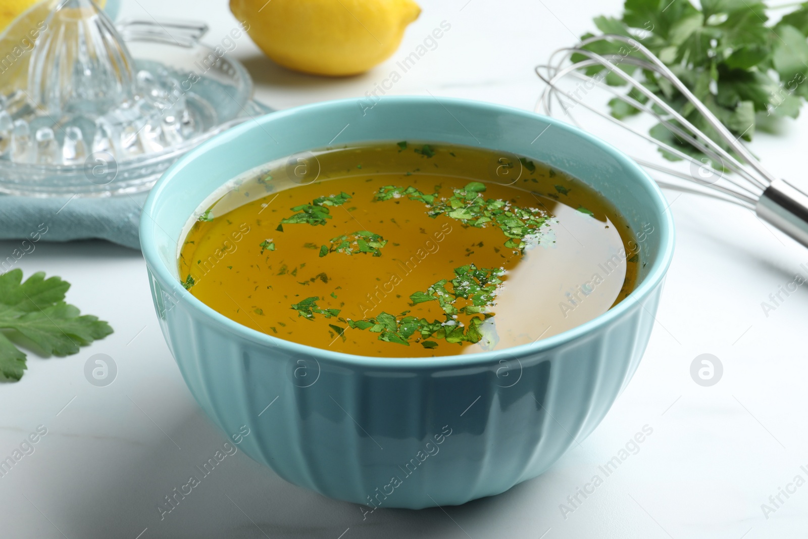 Photo of Bowl with lemon sauce on white table, closeup. Delicious salad dressing