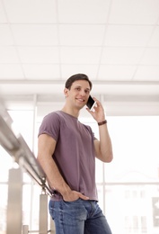 Photo of Portrait of confident young man with mobile phone, indoors