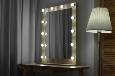 Photo of Beautiful mirror with light bulbs and lamp in makeup room