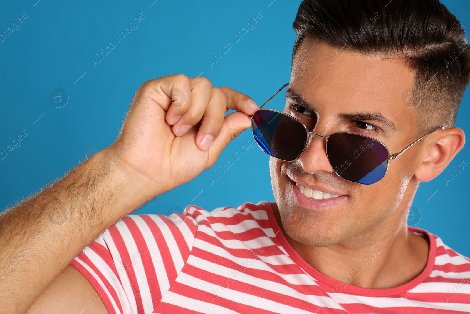 Photo of Handsome man wearing sunglasses on blue background, closeup