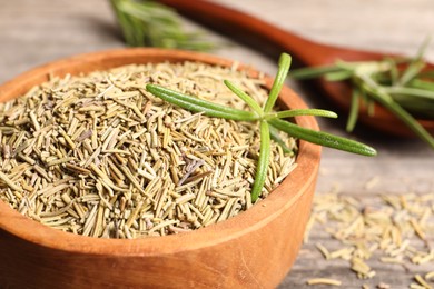 Dry and fresh rosemary in wooden bowl on table, closeup