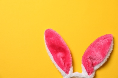 Photo of Funny Easter bunny ears on color background, top view with space for text