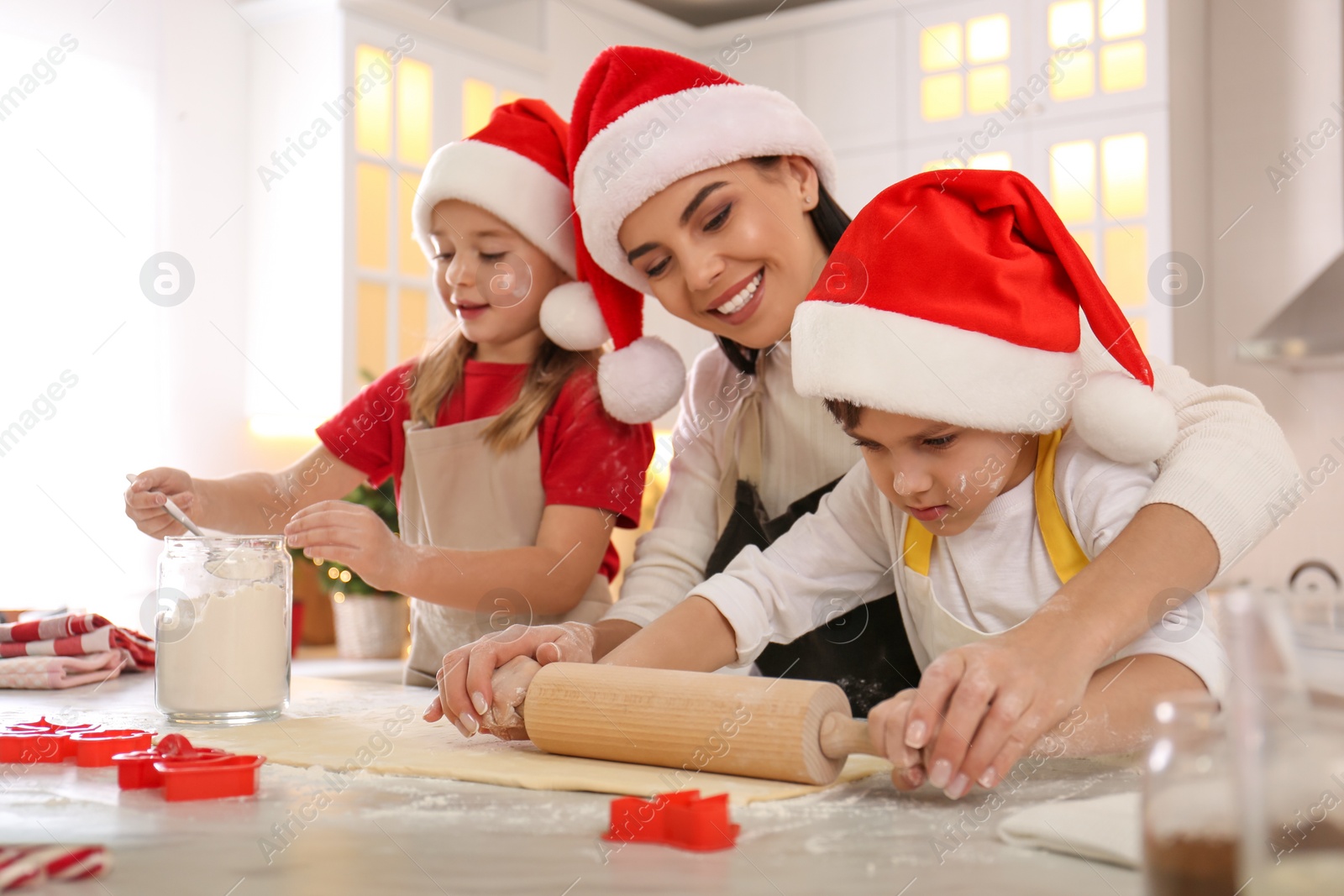 Photo of Mother and her cute little children making Christmas cookies in kitchen