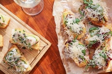 Delicious bruschettas served on wooden table, flat lay