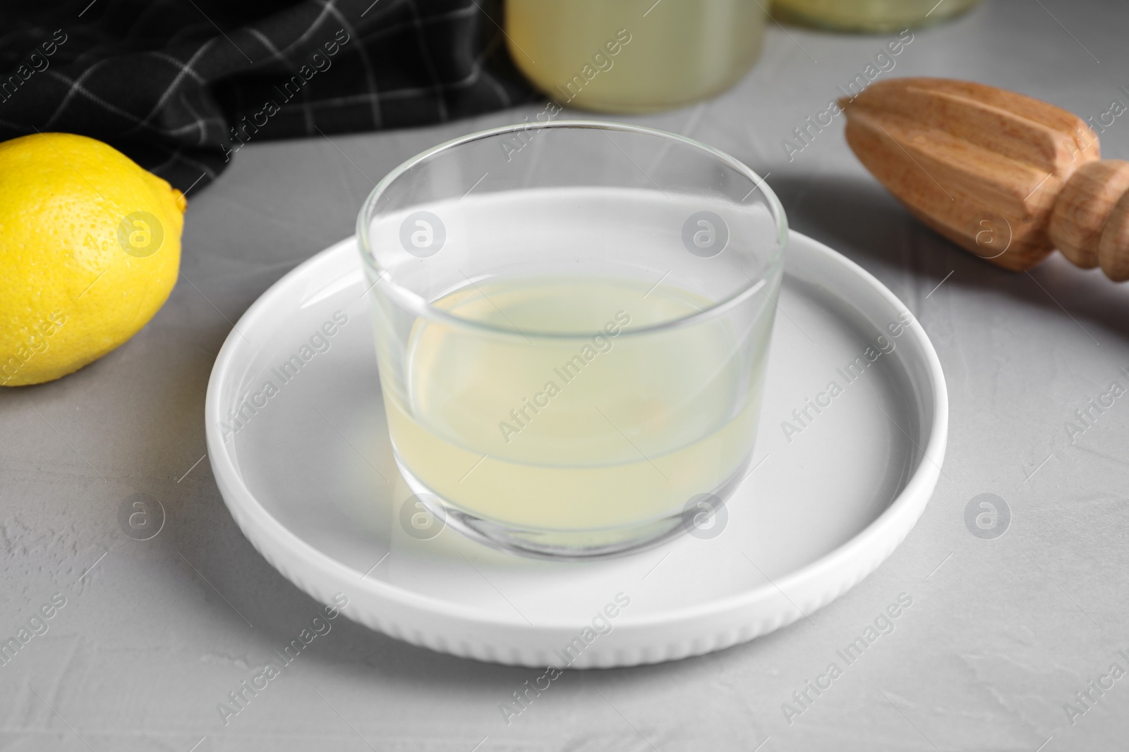 Photo of Freshly squeezed lemon juice in glass bowl on grey table