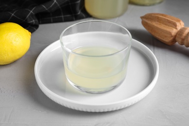 Photo of Freshly squeezed lemon juice in glass bowl on grey table