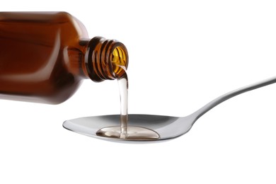 Pouring syrup into spoon from bottle isolated on white, closeup. Cough and cold medicine