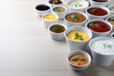 Photo of Many different sauces and herbs on wooden table. Space for text
