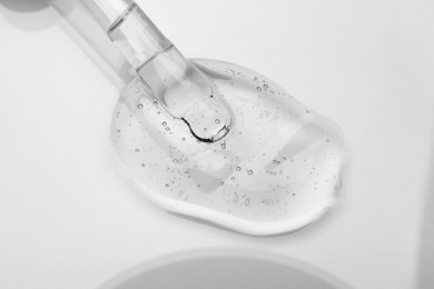 Dripping cosmetic oil from pipette onto light surface, closeup
