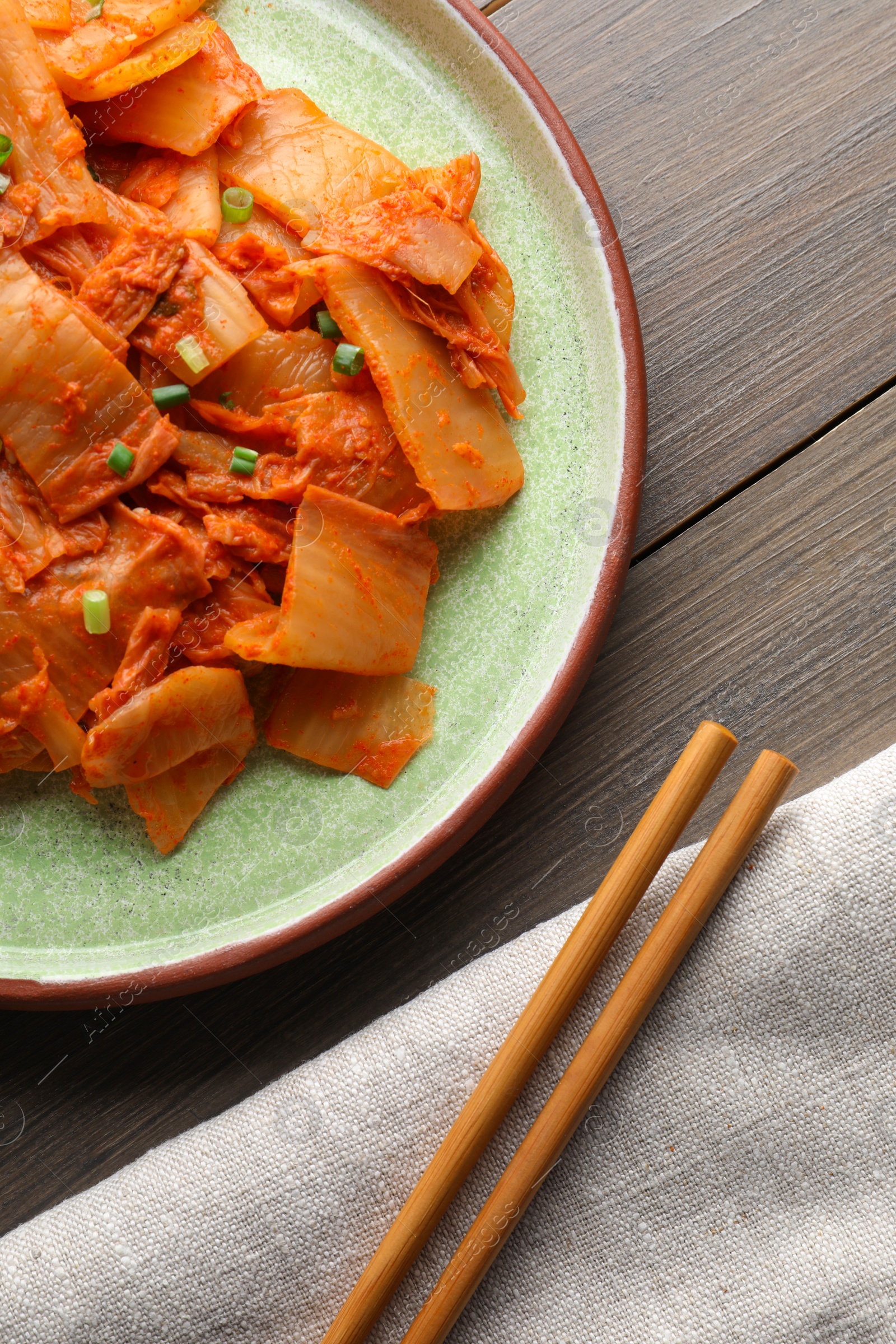 Photo of Delicious kimchi with Chinese cabbage served on wooden table, flat lay