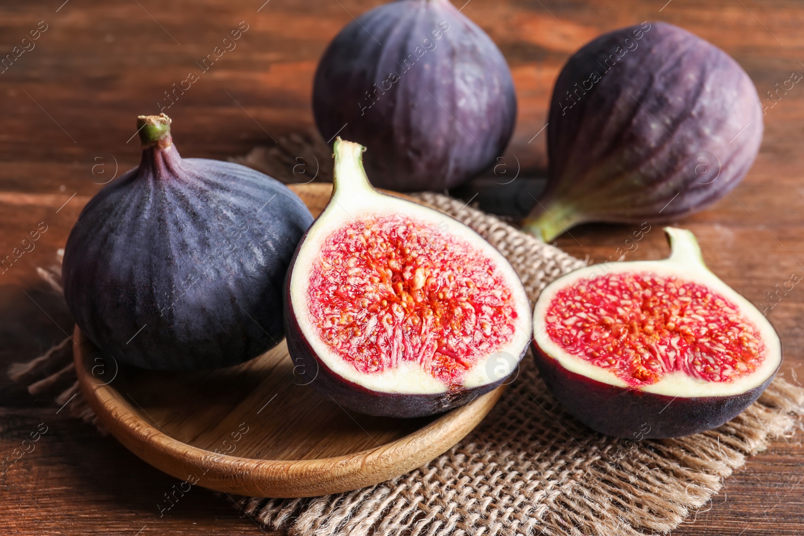 Photo of Plate with fresh ripe figs on wooden background. Tropical fruit