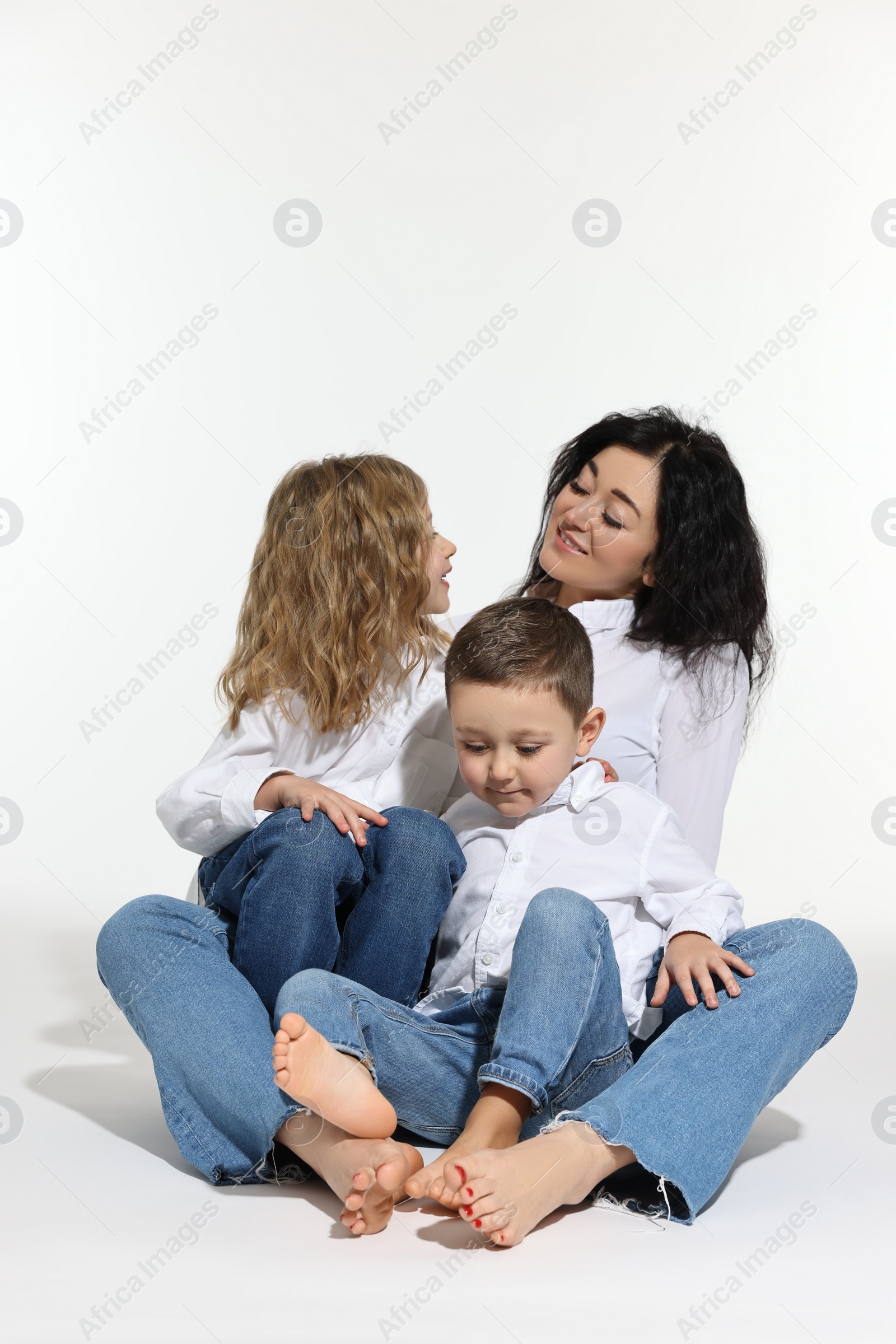 Photo of Little children with their mother sitting together on white background