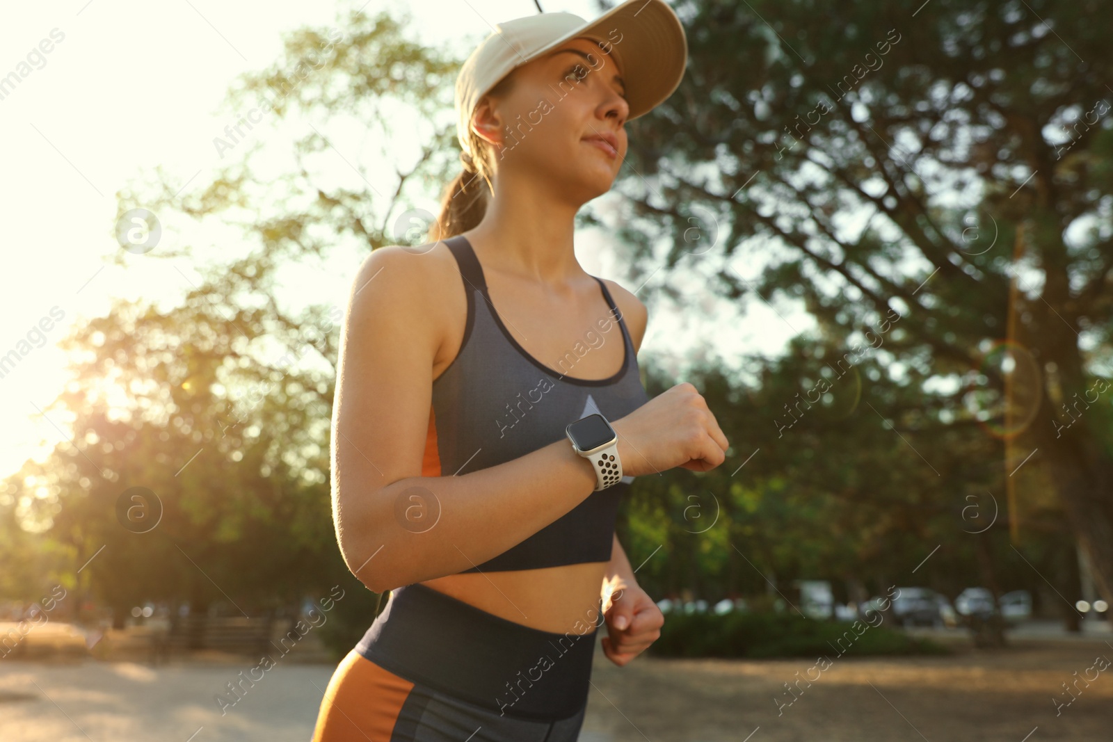 Photo of Woman wearing modern smart watch during training outdoors