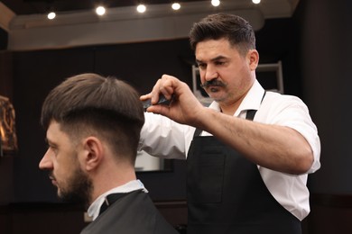 Photo of Professional hairdresser making stylish haircut in barbershop