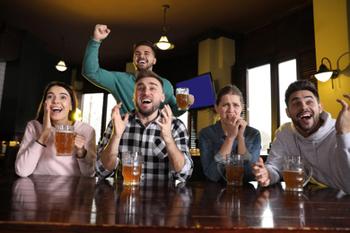 Group of friends watching football in sport bar