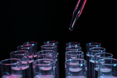 Photo of Dripping reagent into test tube on black background, closeup. Laboratory analysis