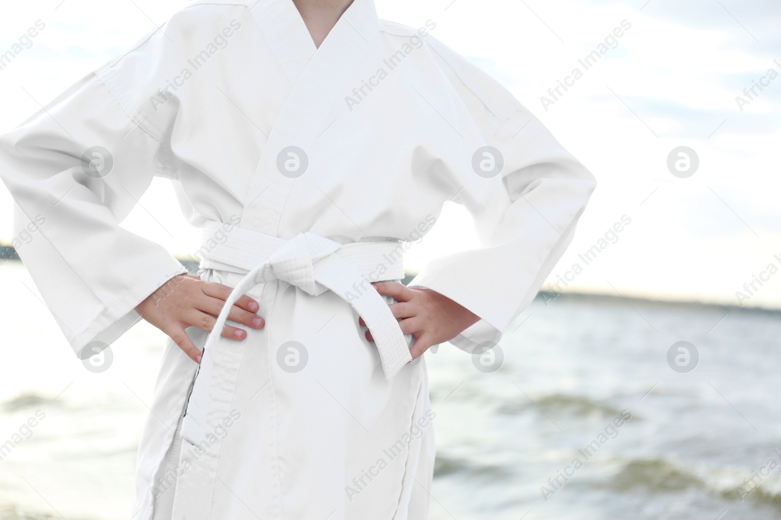 Photo of Cute little girl in kimono near river, closeup. Karate practicing