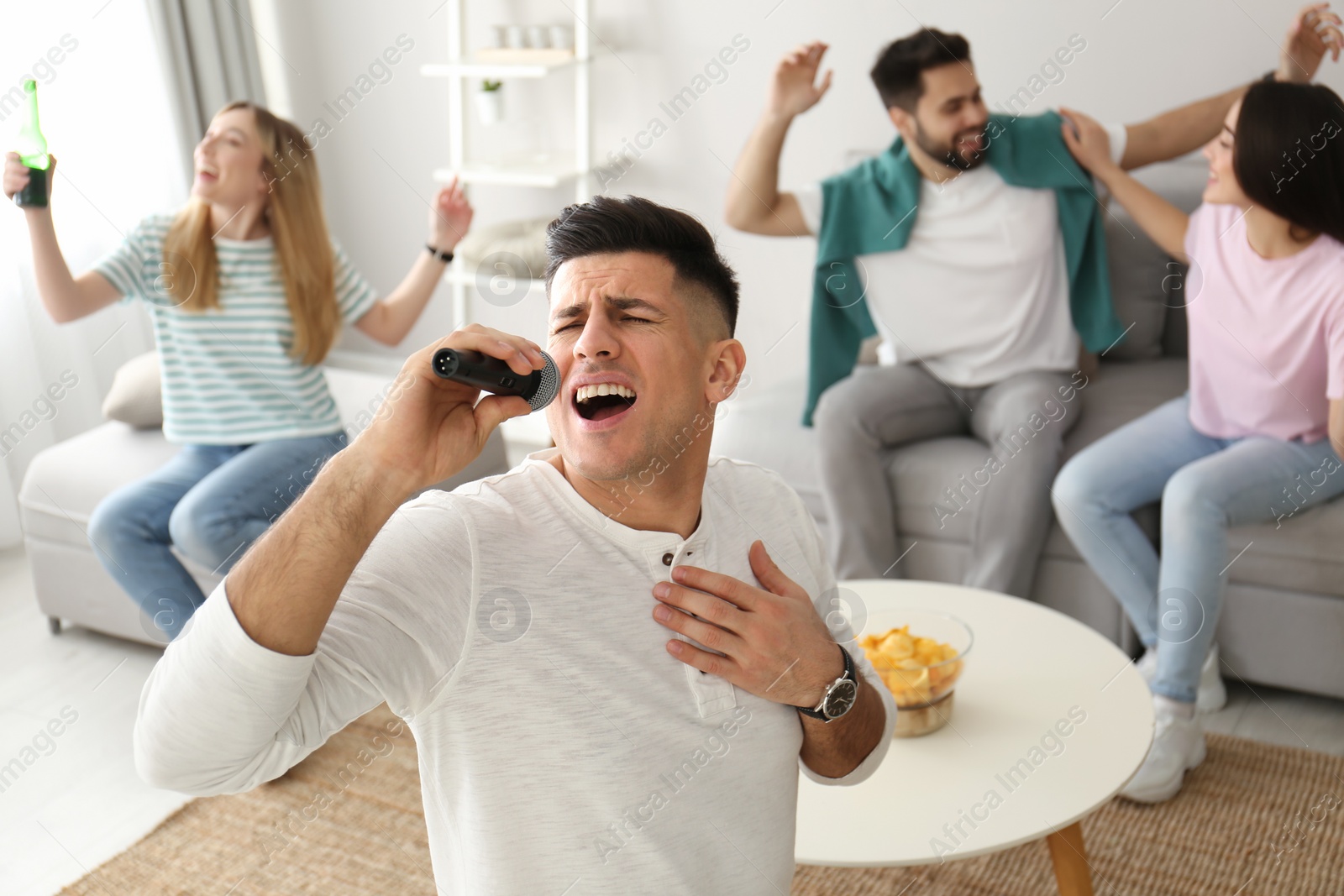 Photo of Man singing karaoke with friends at home