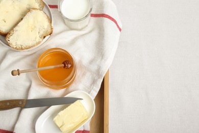 Photo of Sandwiches with butter, honey and milk on white table, top view. Space for text
