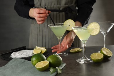 Photo of Woman making delicious Margarita cocktail at grey table, closeup