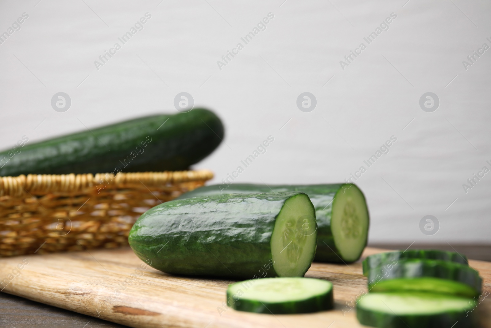 Photo of Fresh whole and cut cucumbers on wooden table, closeup