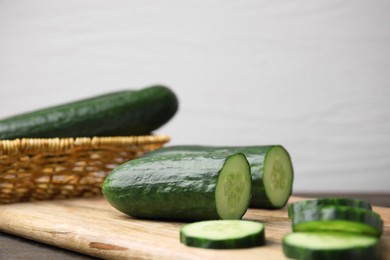 Fresh whole and cut cucumbers on wooden table, closeup