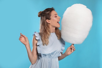 Photo of Portrait of pretty young woman with cotton candy on blue background