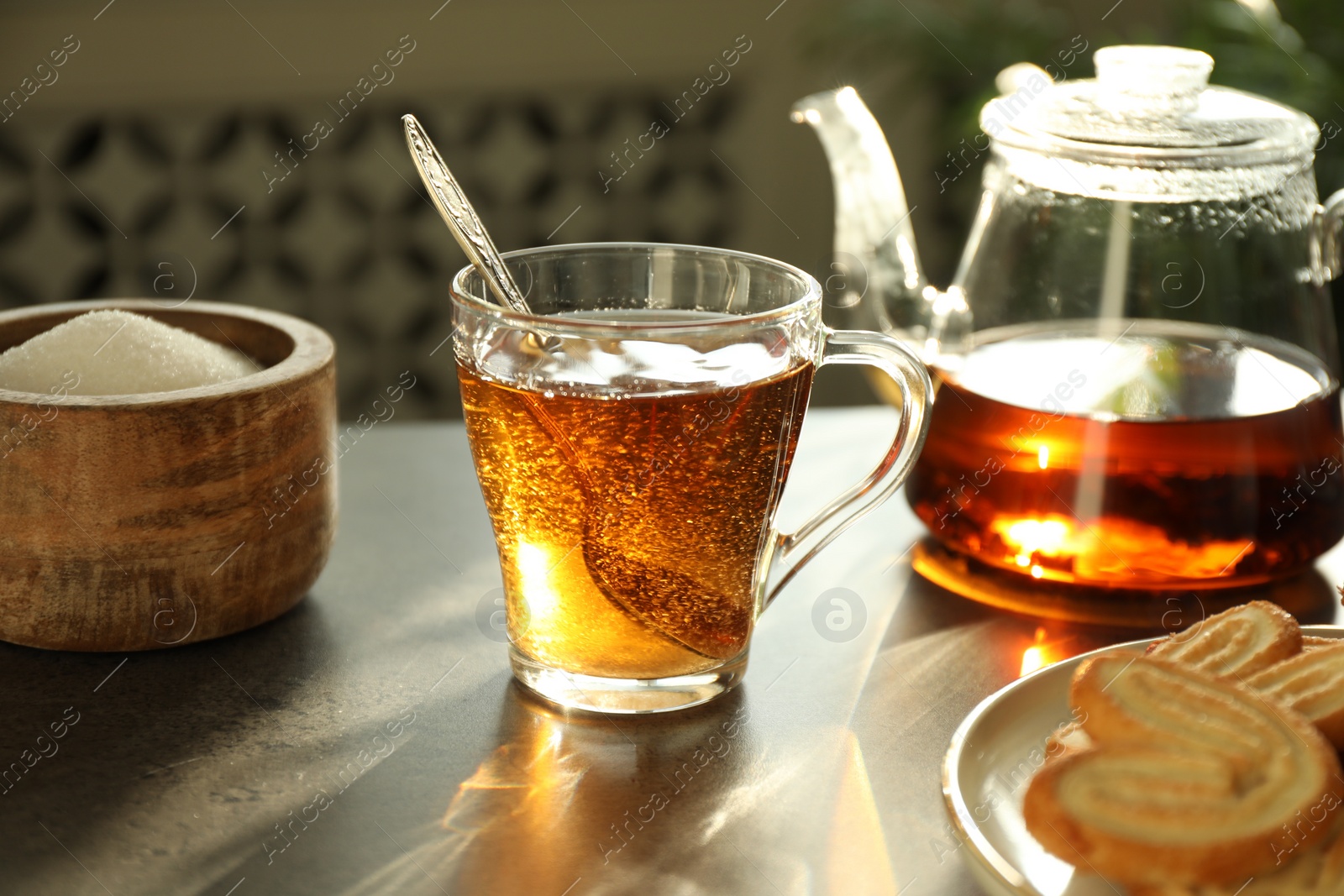 Photo of Tasty tea and sugar on dark table, closeup